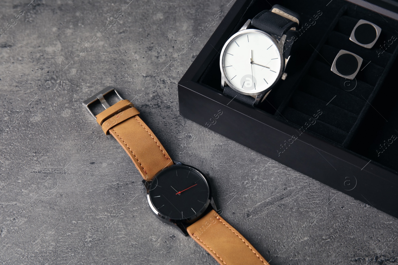 Photo of Composition with stylish wrist watches on gray table. Fashion accessory