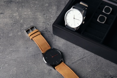 Composition with stylish wrist watches on gray table. Fashion accessory