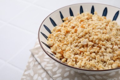 Fried ground meat in bowl on white tiled table, closeup. Space for text