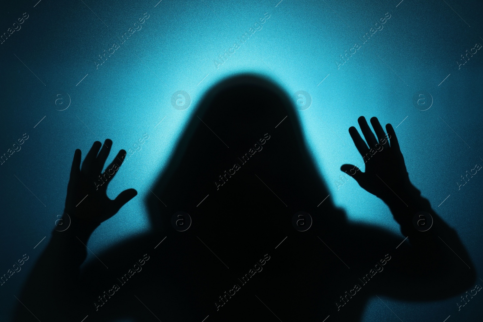 Photo of Silhouette of ghost behind glass against blue background