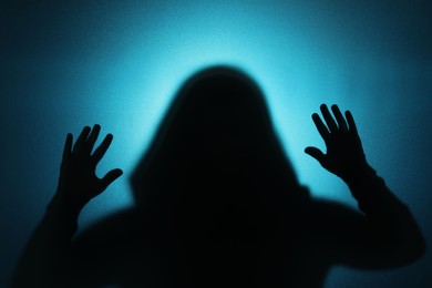 Photo of Silhouette of ghost behind glass against blue background
