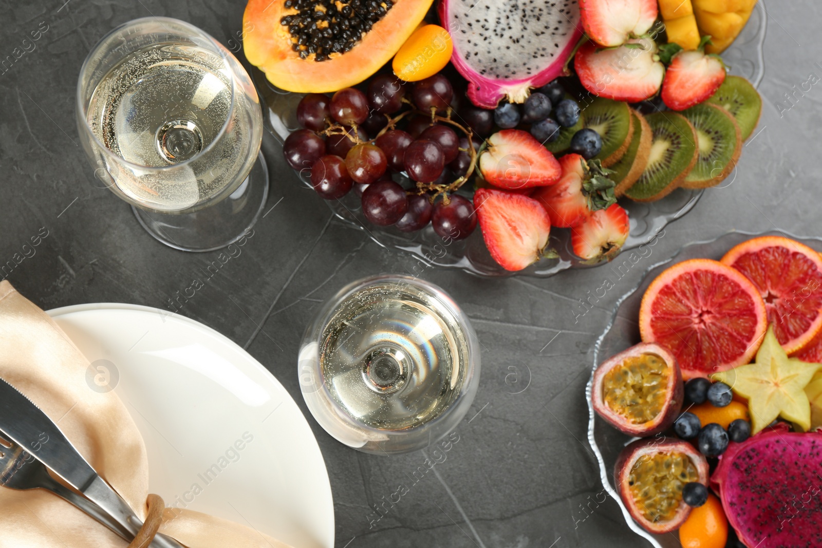 Photo of Delicious exotic fruits and wine on grey table