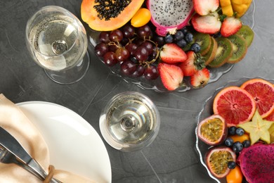 Delicious exotic fruits and wine on grey table