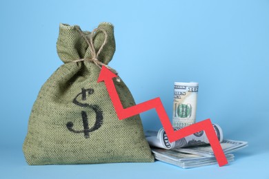 Photo of Economic profit. Money bag, banknotes and arrow on light blue background
