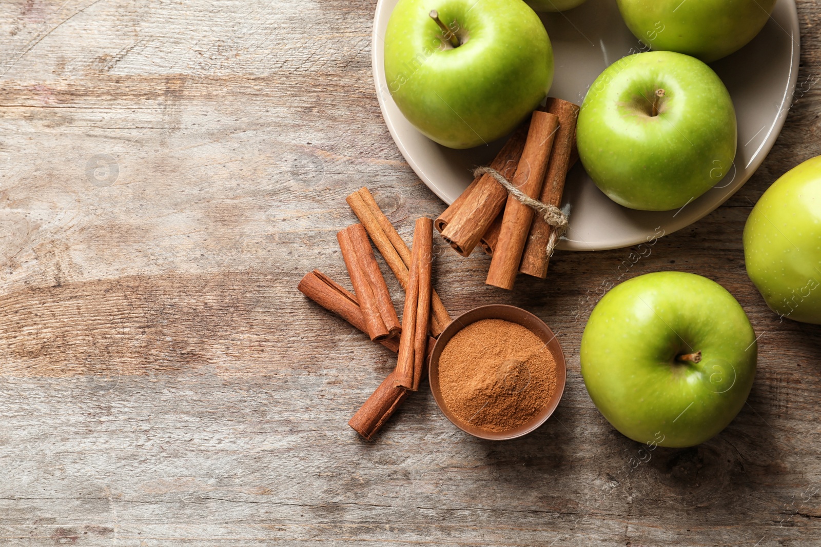 Photo of Fresh apples with cinnamon sticks and powder on wooden table, top view