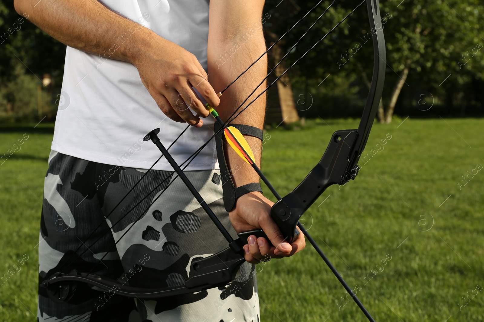 Photo of Man with bow and arrow practicing archery in park, closeup