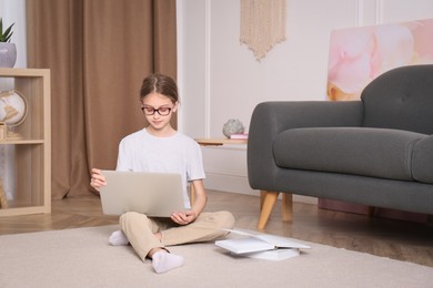 Photo of Girl with laptop and books sitting on floor at home