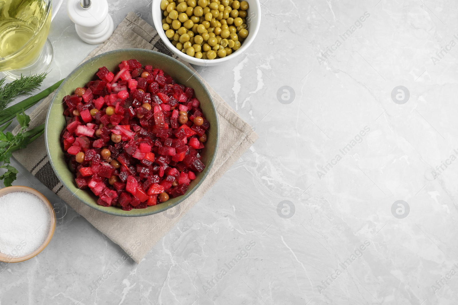 Photo of Bowl of delicious fresh vinaigrette salad and ingredients on light grey marble table, flat lay. Space for text