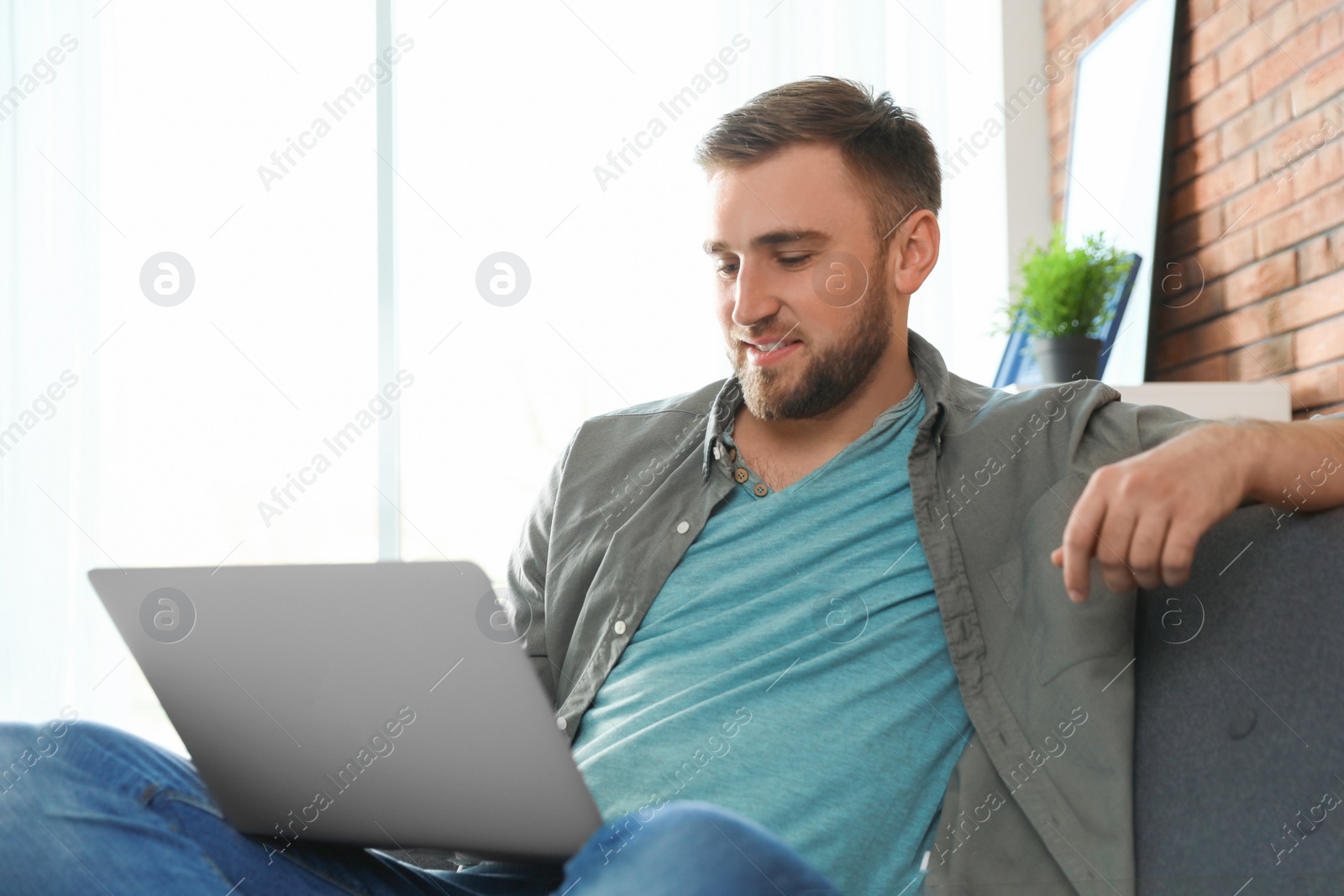 Photo of Young man using laptop in living room