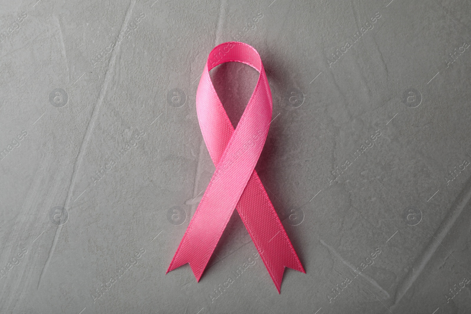 Photo of Pink ribbon on grey background, top view. Breast cancer awareness concept