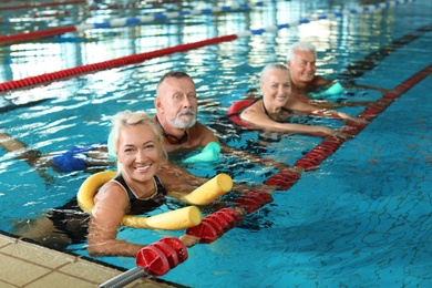 Sportive senior people doing exercises in indoor swimming pool