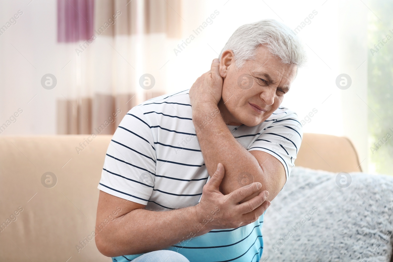 Photo of Mature man suffering from neck pain at home