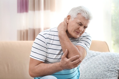 Photo of Mature man suffering from neck pain at home