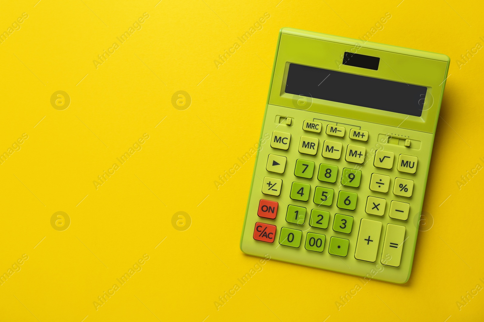 Photo of Green calculator on yellow background, top view. Space for text