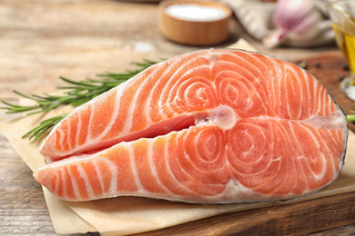 Photo of Fresh raw salmon with rosemary on wooden table. Fish delicacy