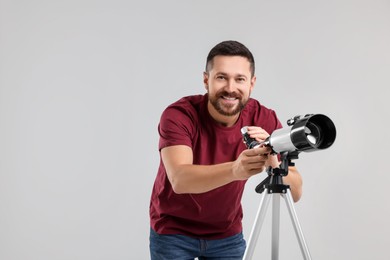 Smiling astronomer with telescope on light grey background. Space for text
