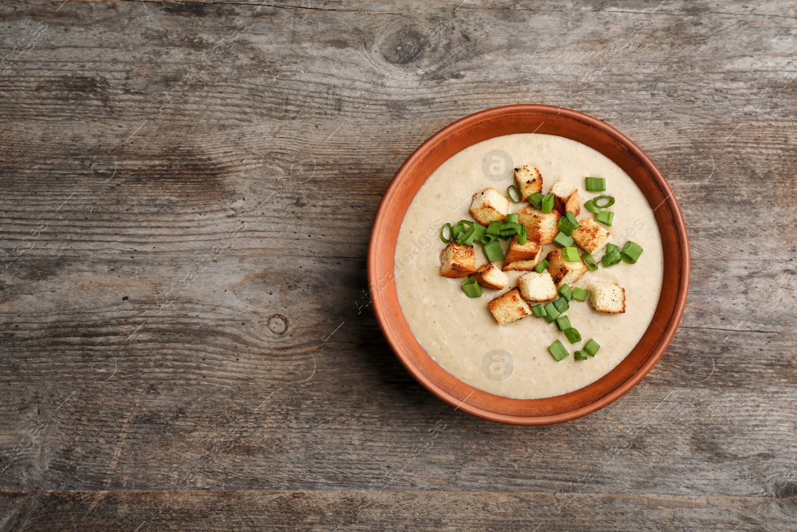 Photo of Bowl of fresh homemade mushroom soup on wooden background, top view with space for text