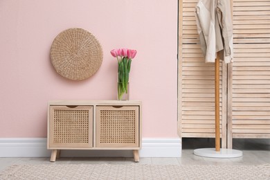 Photo of Console table with drawers and coat stand in hallway. Interior design
