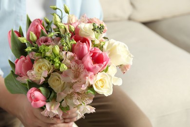 Photo of Man holding bouquet of beautiful flowers indoors, closeup