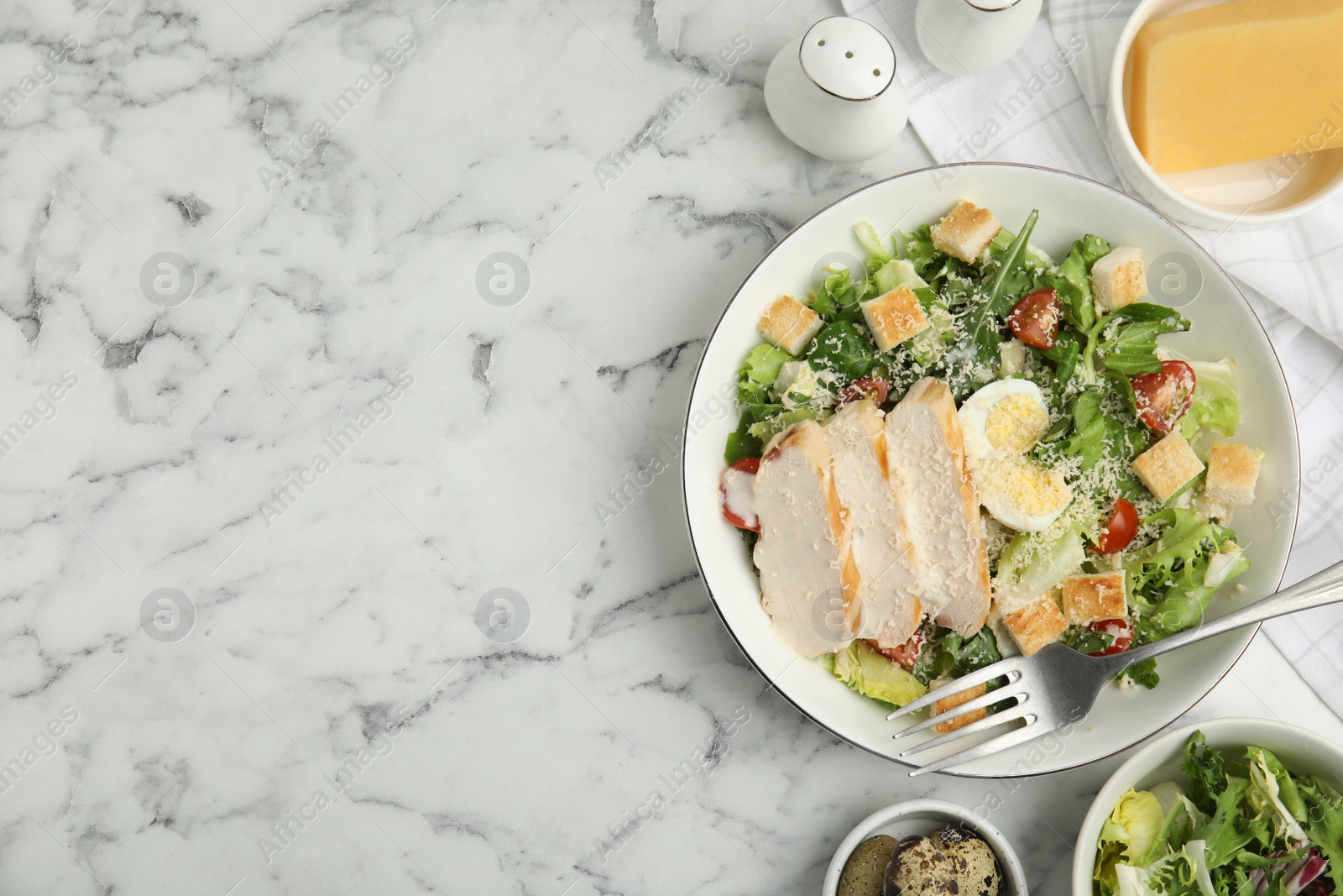 Photo of Delicious Caesar salad in bowl on white marble table, flat lay. Space for text