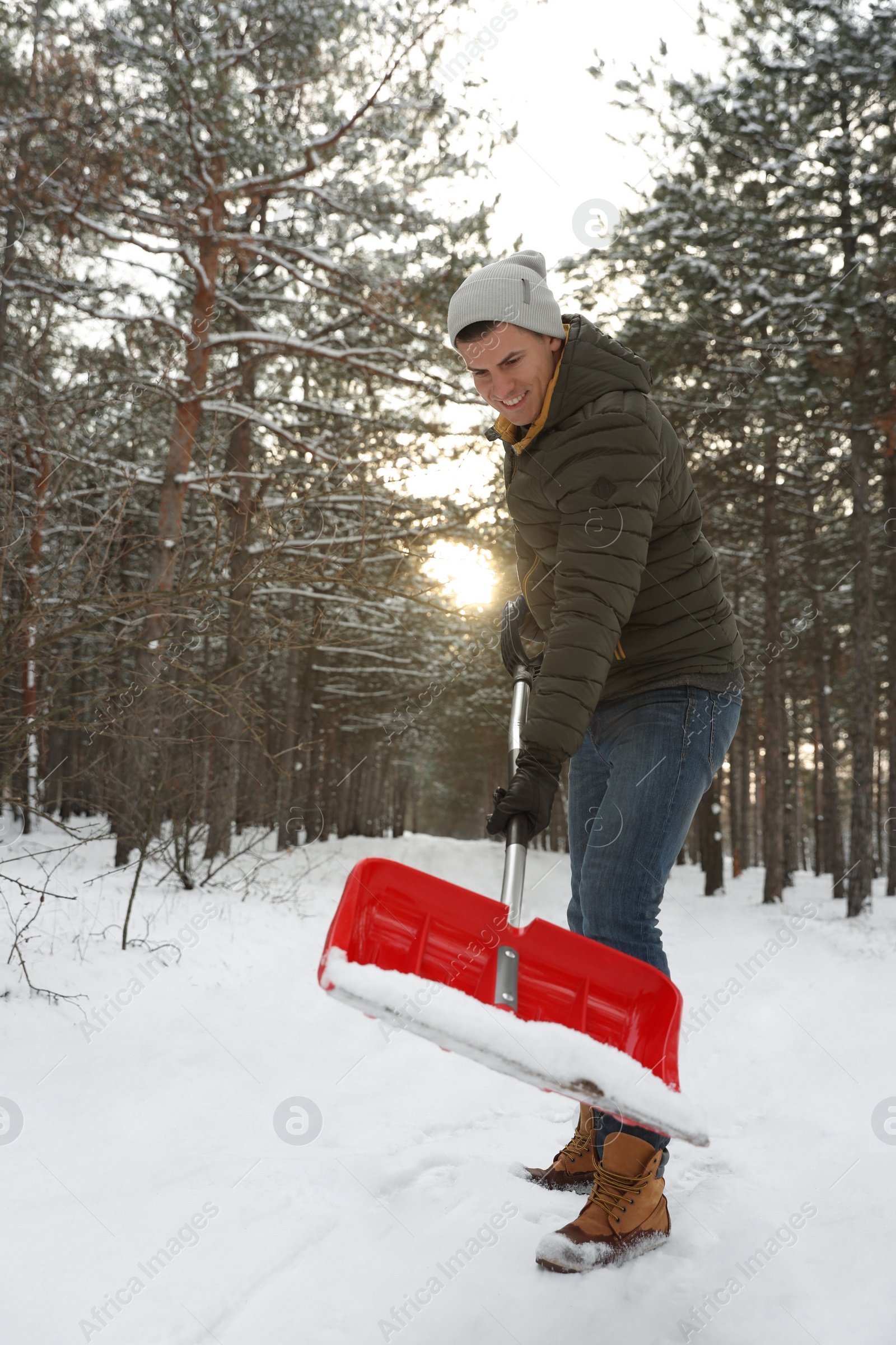Photo of Man removing snow with shovel outdoors on winter day