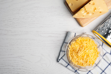 Flat lay composition with grated cheese on white wooden table, space for text
