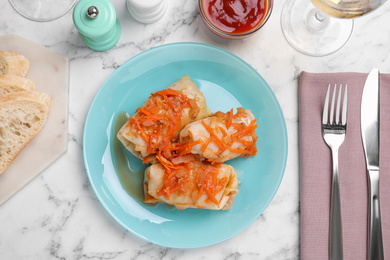 Photo of Delicious cabbage rolls served on white marble table, flat lay