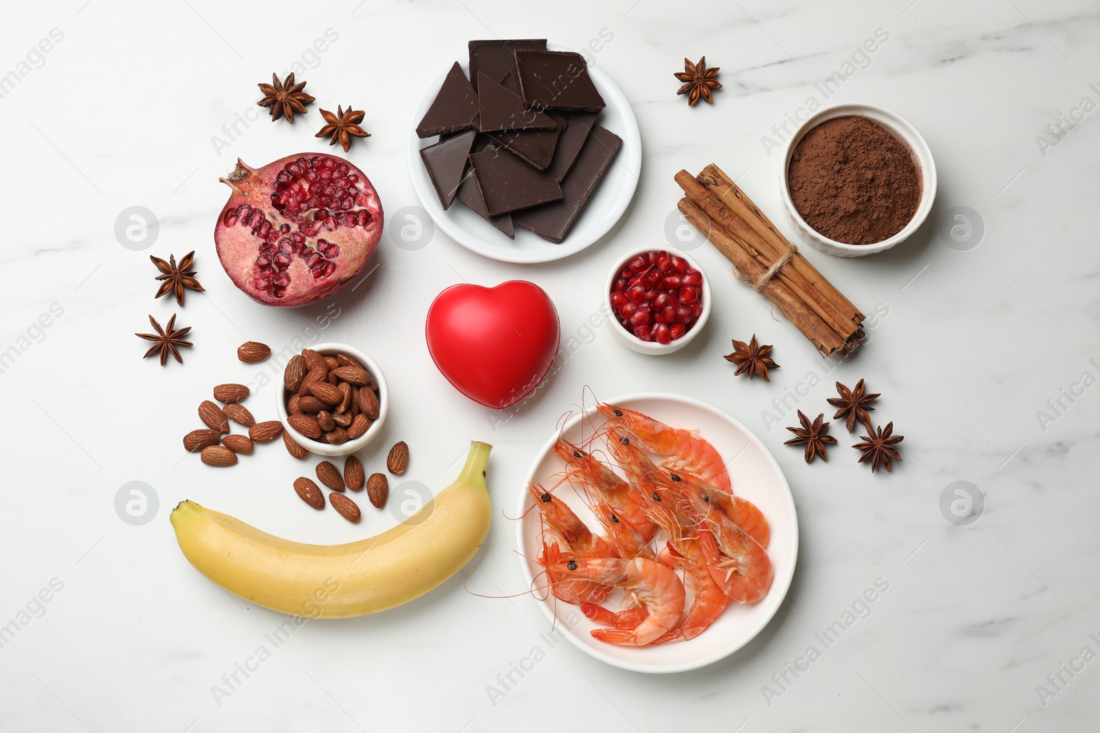 Photo of Natural aphrodisiac. Different food products and red decorative heart on white marble table, flat lay