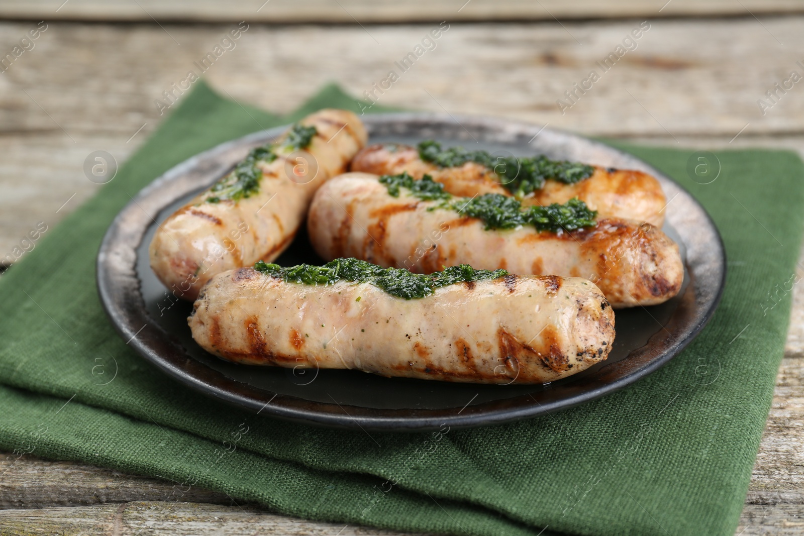 Photo of Tasty fresh grilled sausages with sauce on wooden table