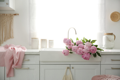 Bouquet of beautiful pink peonies in kitchen sink