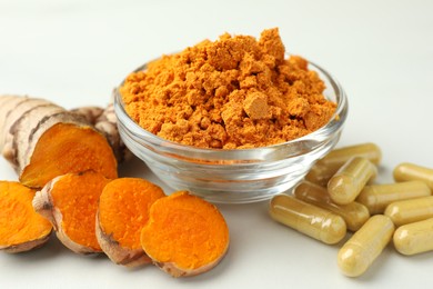 Photo of Aromatic turmeric powder, pills and raw root on white table, closeup