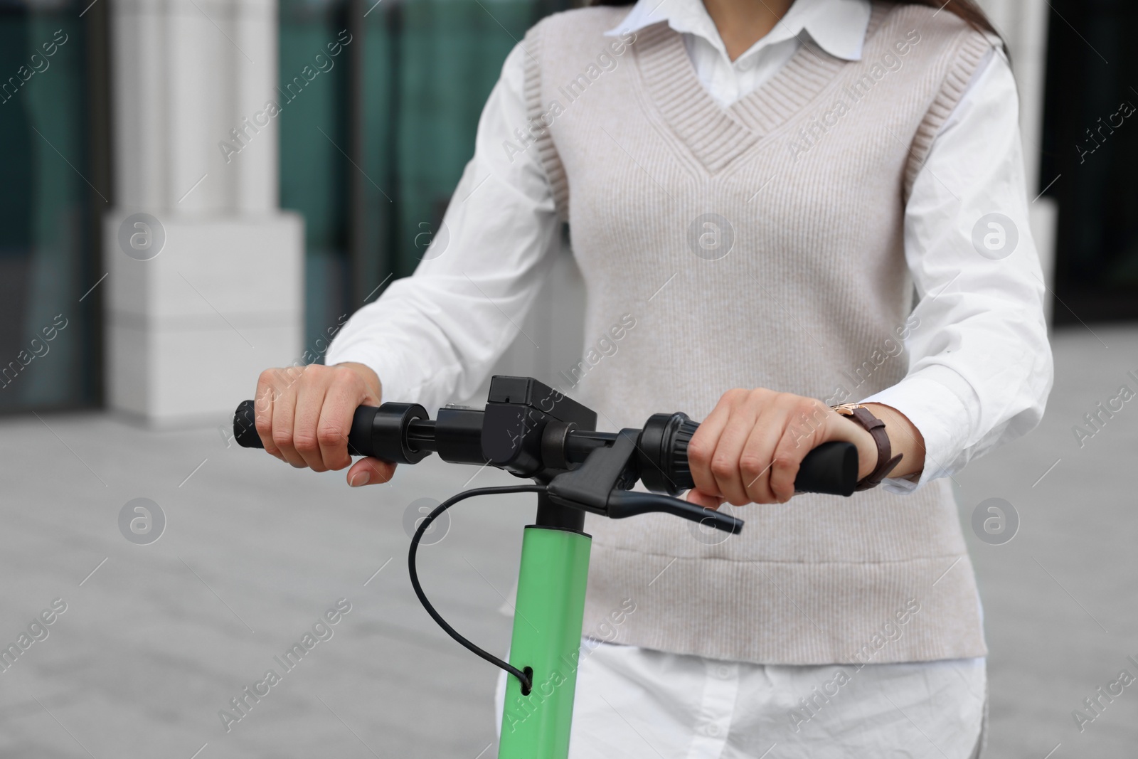 Photo of Businesswoman riding electric kick scooter on city street, closeup