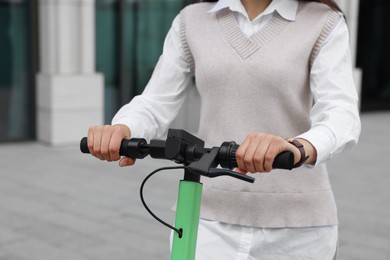 Photo of Businesswoman riding electric kick scooter on city street, closeup