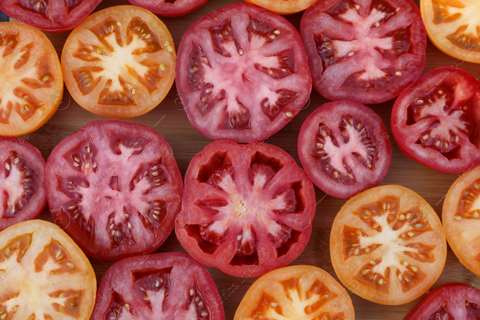 Photo of Cut tomatoes of different sorts on wooden table, flat lay