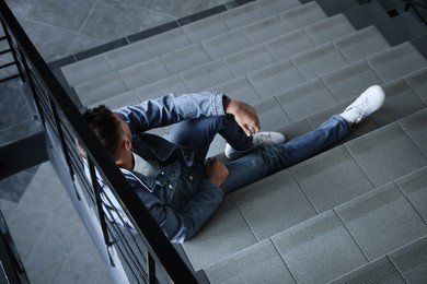 Photo of Upset man sitting on stairs indoors. Loneliness concept