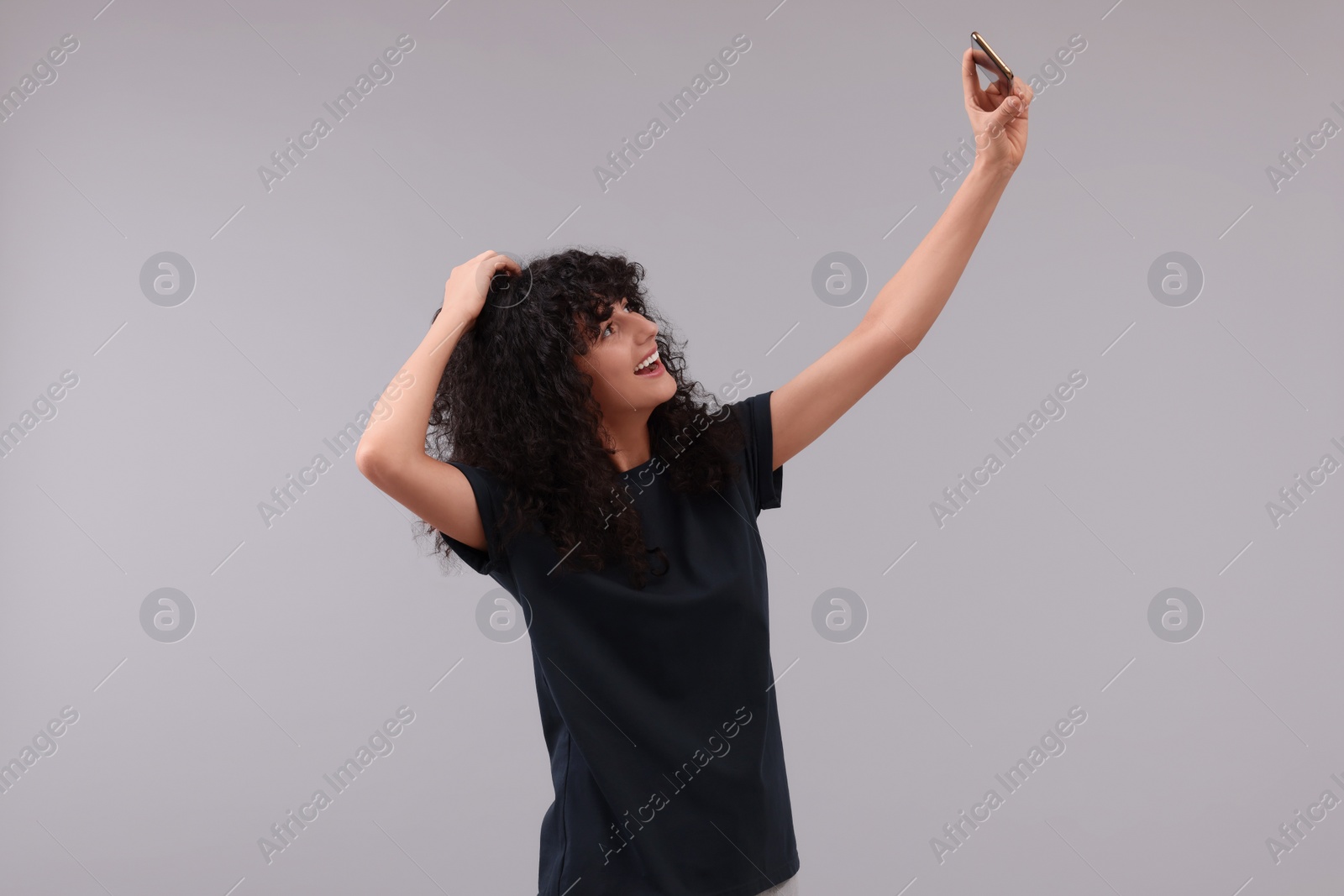 Photo of Beautiful young woman taking selfie on light grey background