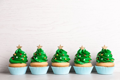 Photo of Christmas tree shaped cupcakes on table. Space for text