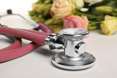 Photo of Stethoscope and eustoma flowers on white background, closeup. Happy Doctor's Day