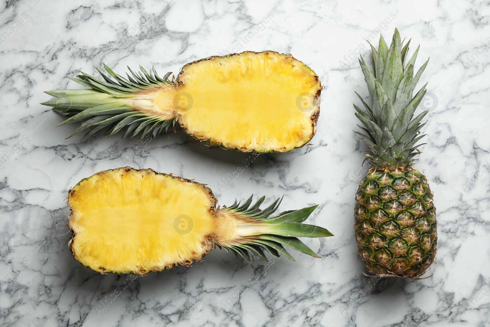 Photo of Fresh whole and cut pineapples on white marble background, top view