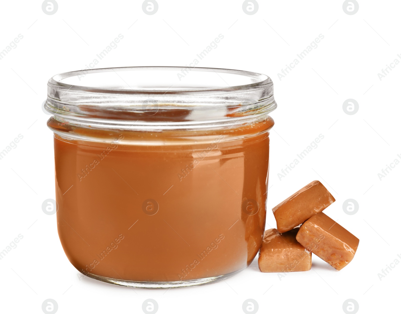 Photo of Jar of tasty caramel sauce and candies isolated on white