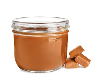 Photo of Jar of tasty caramel sauce and candies isolated on white