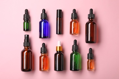 Bottles of essential oils on color background, flat lay. Cosmetic products