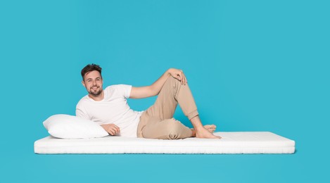 Man lying on soft mattress against light blue background