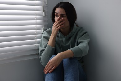 Photo of Sadness. Unhappy woman near window at home