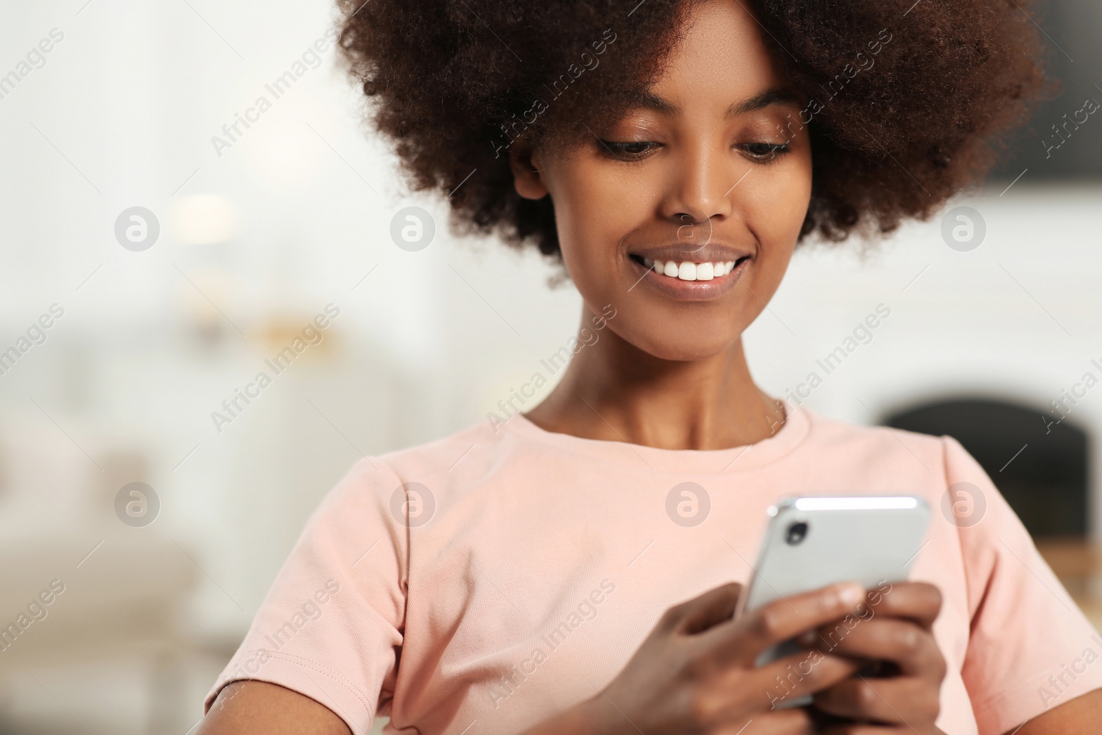 Photo of Smiling African American woman with smartphone at home