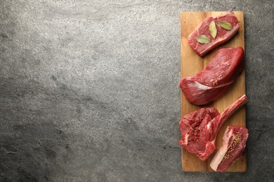 Photo of Pieces of raw beef meat and spices on grey textured table, top view. Space for text