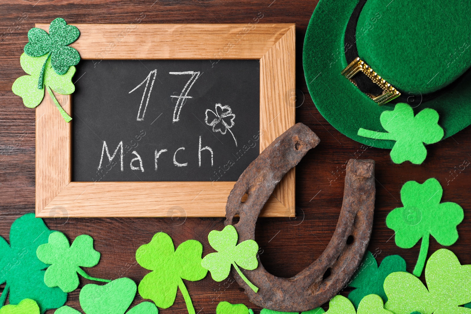 Photo of Flat lay composition with horseshoe and chalkboard on wooden background. St. Patrick's Day celebration