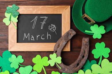Flat lay composition with horseshoe and chalkboard on wooden background. St. Patrick's Day celebration