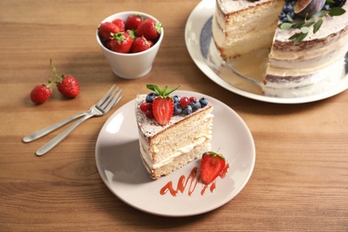 Photo of Piece of delicious homemade cake with fresh berries served on wooden table