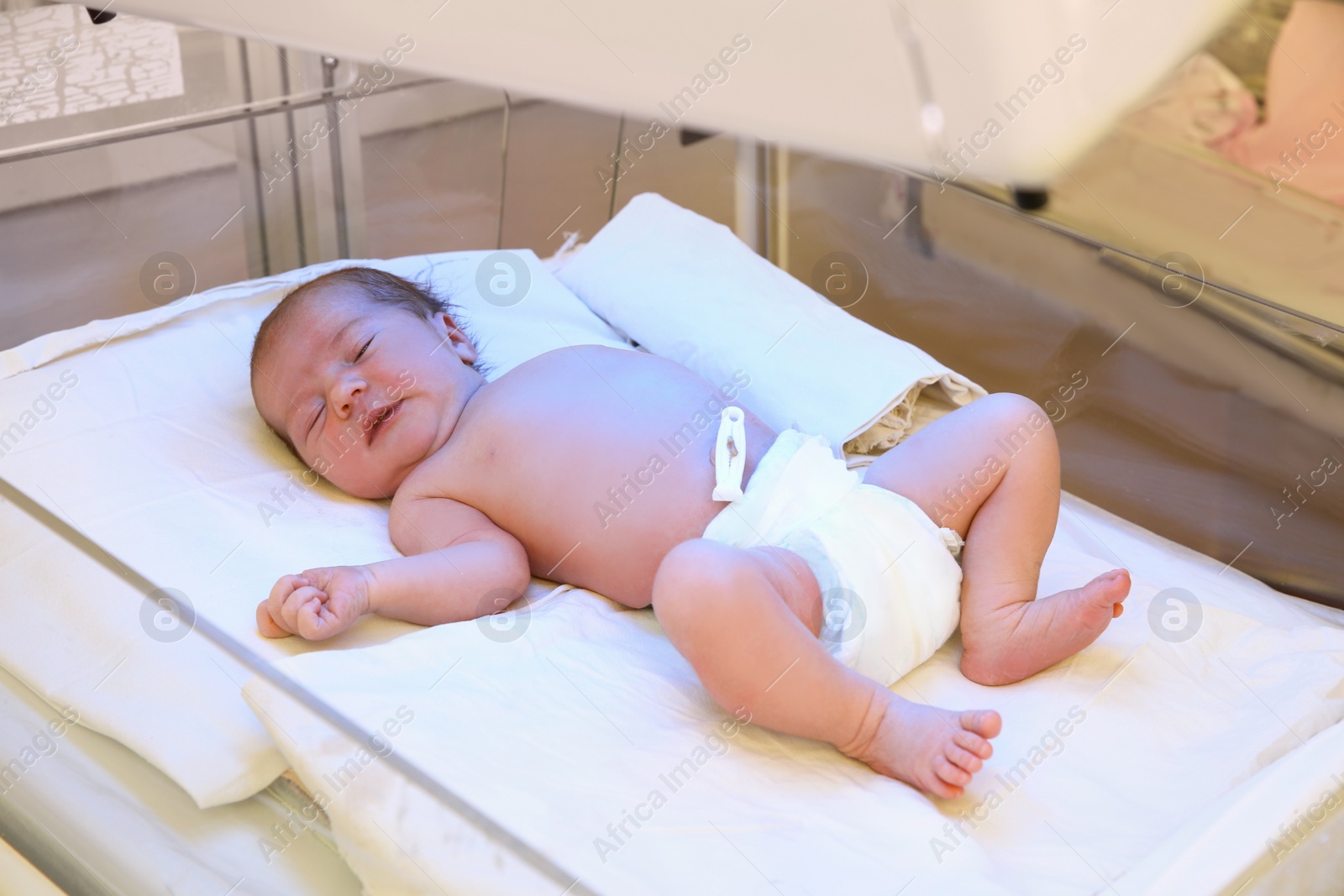 Photo of Newborn child under ultraviolet lamps in hospital